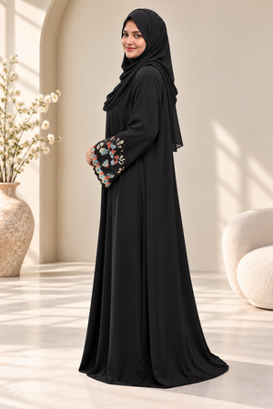 Side view of a black open abaya with colourful floral embroidered sleeves, scalloped cuff detailing and a matching black hijab.emarati.co.uk