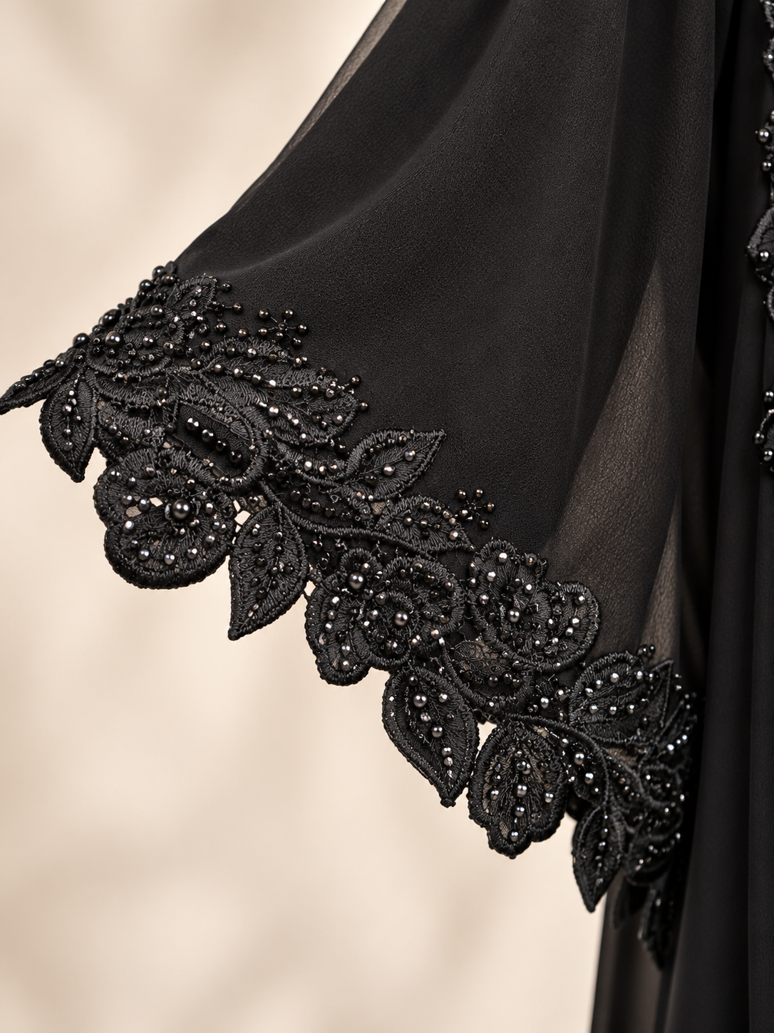 Close-up of 3D floral embellishments and lace HAND on a black net open abaya